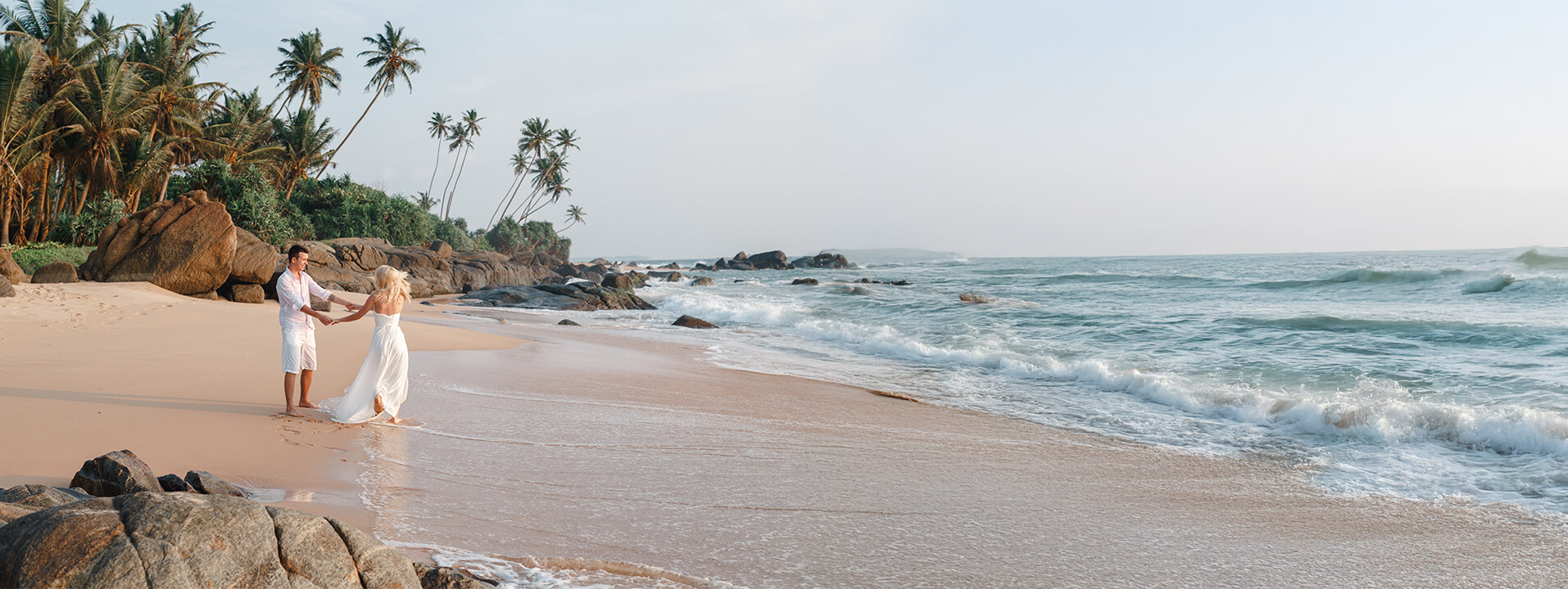 A couple walking along a Sri Lankan beach at golden hour